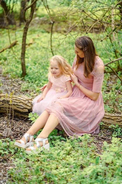 mom and daughter in pink dresses in the spring forest