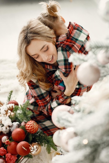 Mom and daughter in plaid pajamas hugging near Christmas tree