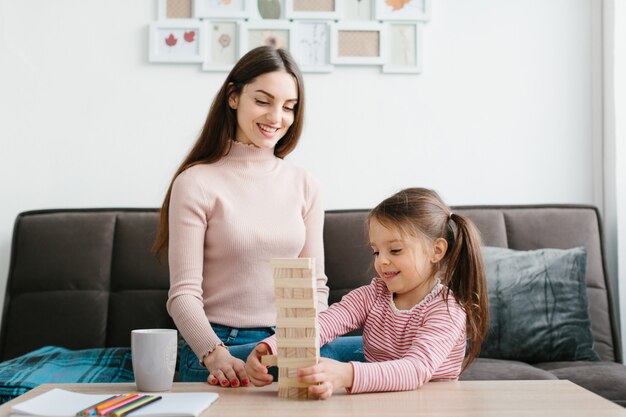 Mom and daughter play a board game in the living room.