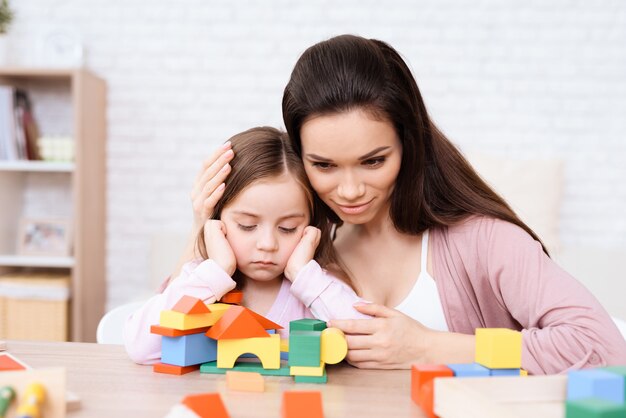 Mom and daughter play together with wooden cubes.