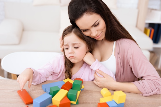 Mom and daughter play together with wooden cubes.
