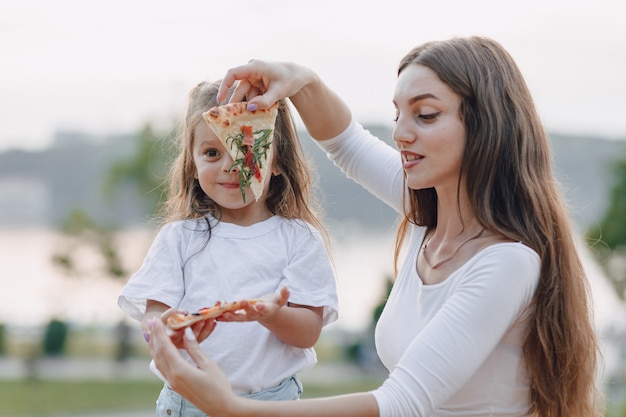 Мама и дочка играют с пиццей на природе