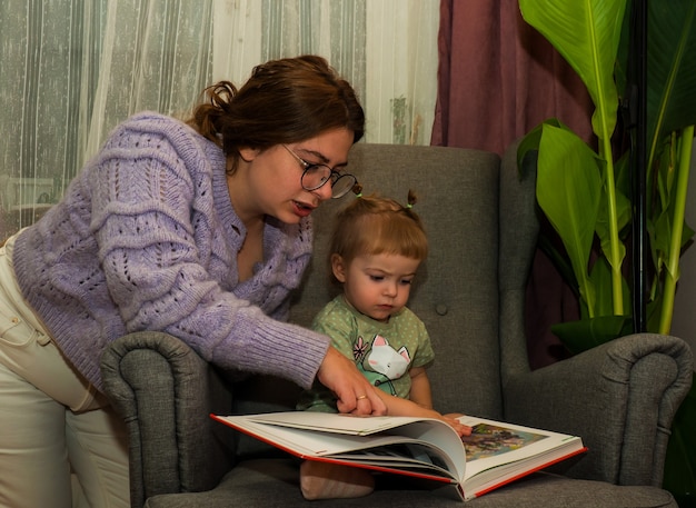 ママと娘が椅子のライフスタイルで本を読む