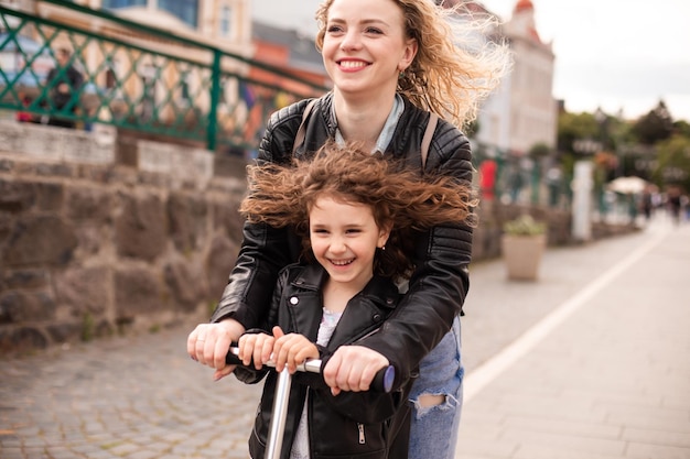 Mom and daughter ride a scooter and have a great time