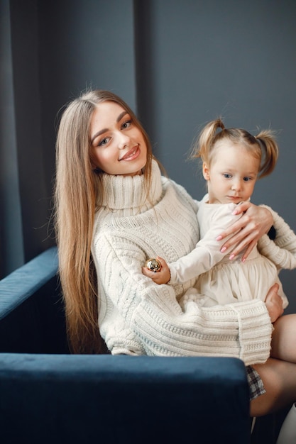 Mom and daughter sitting on a blue velour sofa and looking at camera