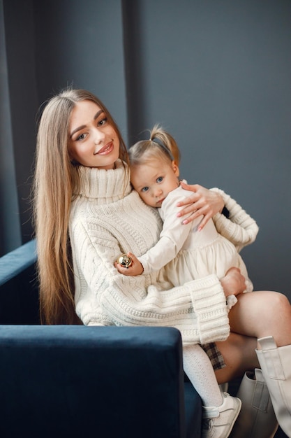 Mom and daughter sitting on a blue velour sofa and looking at camera