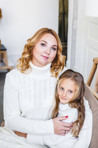 Photo mom and daughter sitting on the couch parent hugs child