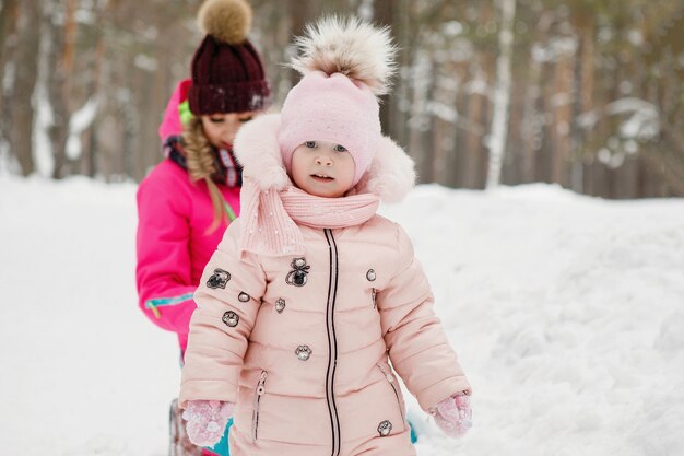 冬の屋外の雪に覆われた公園でママと娘。