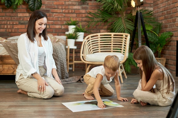 Mom daughter and son put the puzzle together on the floor