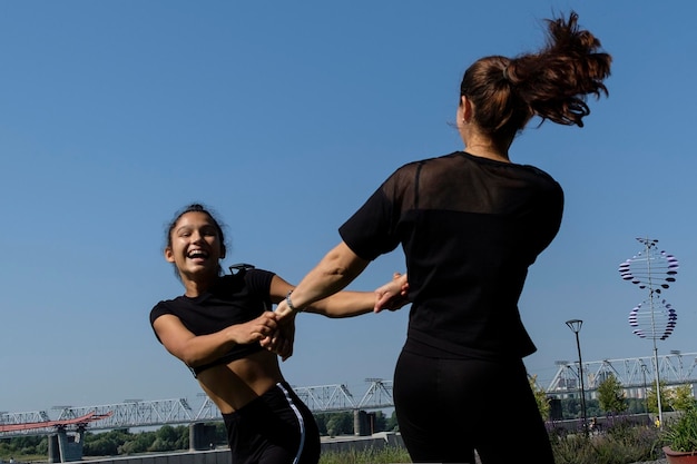 フィットネスをしている公園の堤防で晴れた夏の日にスポーツウェアでママと娘