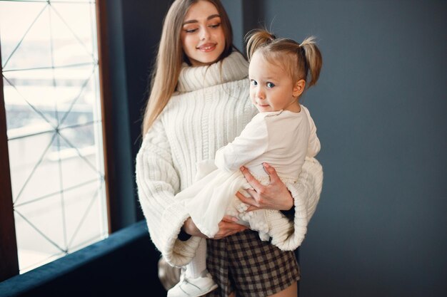 Mom and daughter standing near a big window and hugging