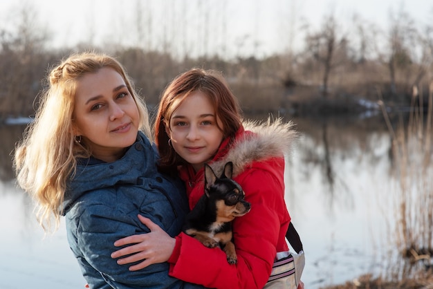 Mom, daughter and their pet chihuahua dog in their arms. Love to the animals. Family values.