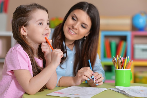 Mom and daughter together draw at the table