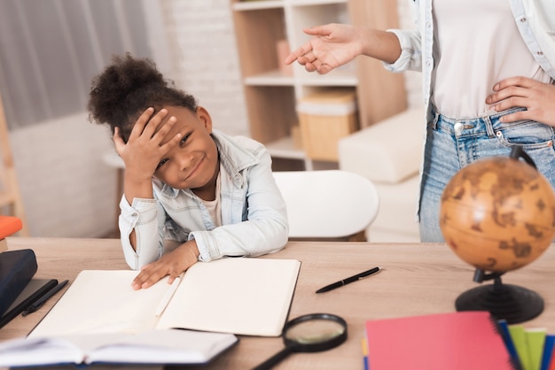 Mom and daughter together do their homework in school.