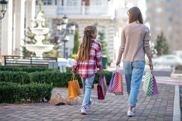 Mom and daughter walking along the street with shopping bags