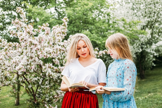 Photo mom and daughter walking in the park, reading books, socializing, laughter and fun, entertainment, hobbies