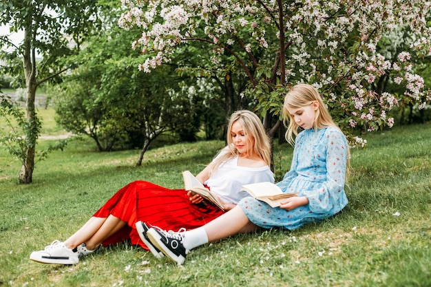 Photo mom and daughter walking in the park, reading books, socializing, laughter and fun, entertainment, hobbies