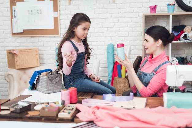 Mom and daughter work together in sewing workshop.