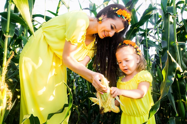 Mom and daughter in yellow dresses in a cornfield