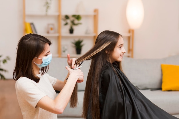 Foto mamma che fa taglio di capelli ragazza