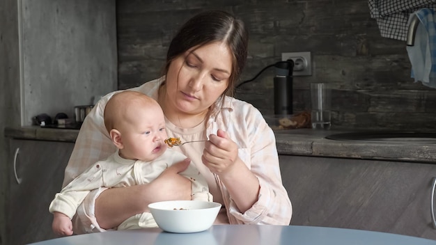 Mom eats cereals with baby sitting on lap and watching food