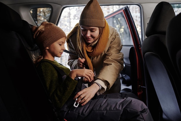 Mom fastening daughter with seat belts