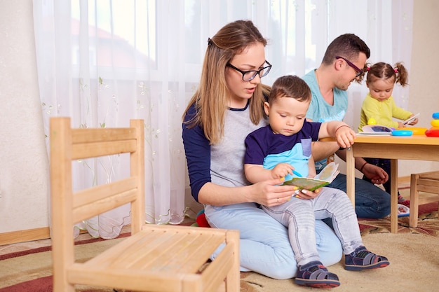 Mom and father read a book with the children in room