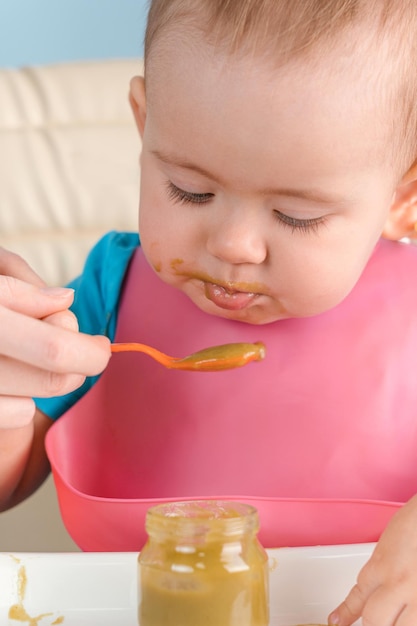 写真 ママは赤ちゃんに 1217 か月の緑の野菜のピューレをスプーンで食べさせます 縦の写真