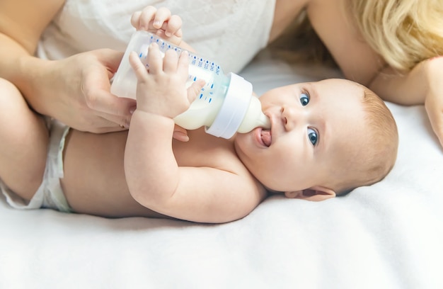 Mom feeds the baby with a bottle