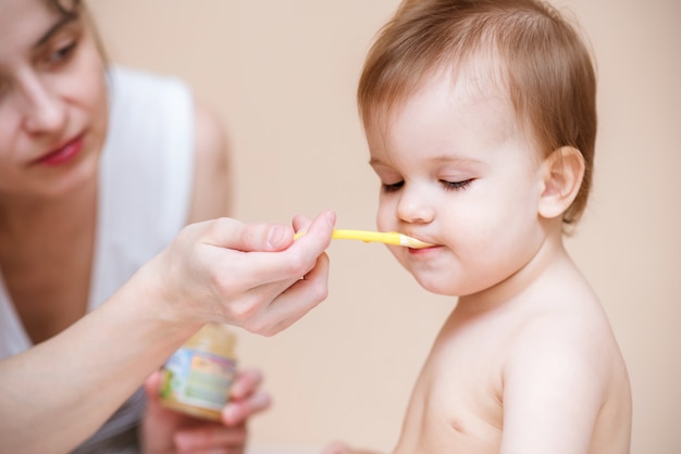 Mom feeds the baby with fruit puree