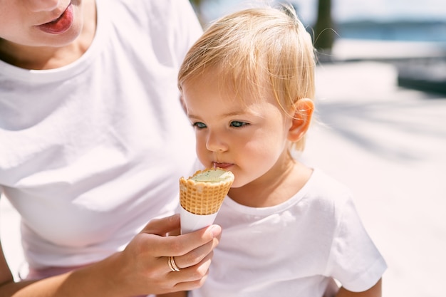 Mom feeds ice cream to little girl portrait