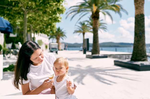 Mom feeds little girl ice cream in a cafe