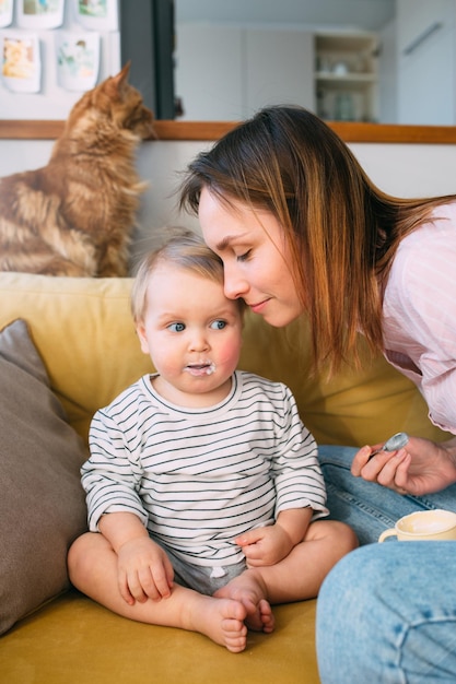 Mom feeds a small child at home with yogurt from a spoon family concept