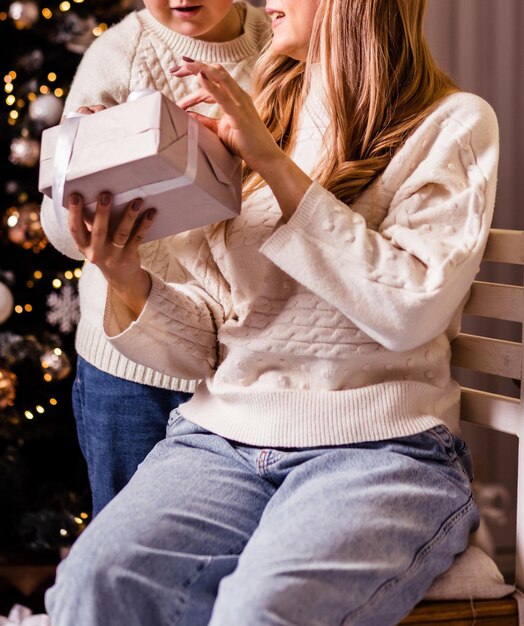 ママは息子にクリスマスプレゼントをあげます。ママと息子は贈り物を見て笑顔。写真