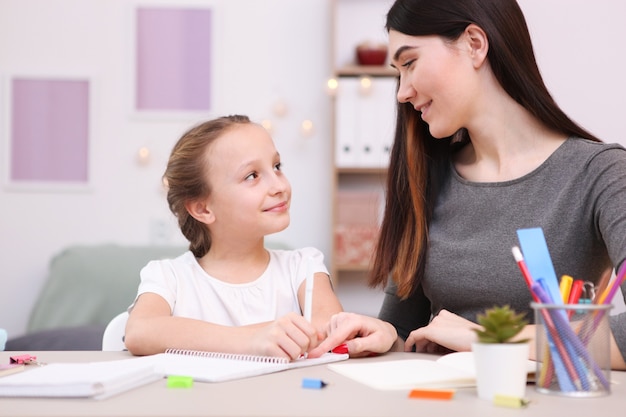 ママは女の子が宿題をするのを手伝う子供と両親