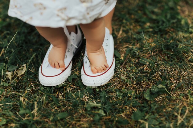 Mom helps to make the child's first steps on the green grass