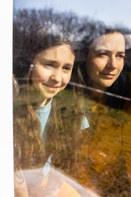 Foto mamma e sua figlia ammirano la bella giornata al chiuso