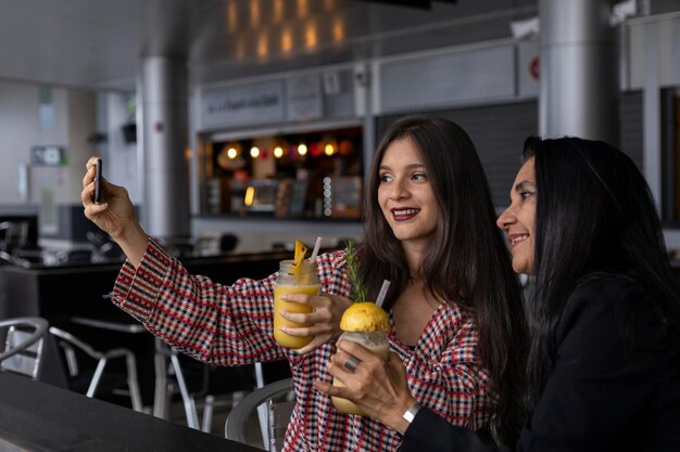 Mom and her Latin American daughter chat and share a fruit drink while taking a picture Mother's Day and healthy living concepts