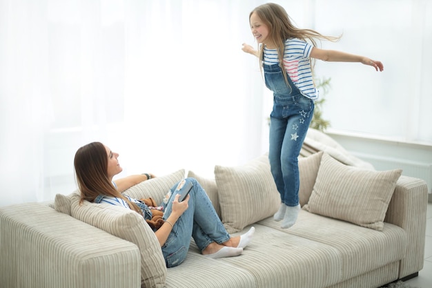 Mom and her little daughter are playing on the couch in the living room photo with copy space