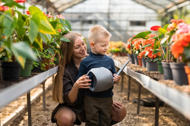 Mom and her son with watering can in the greenhouse