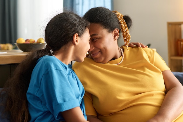 mom and her teenage daughter sitting on sofa at home and enjoying the time together
