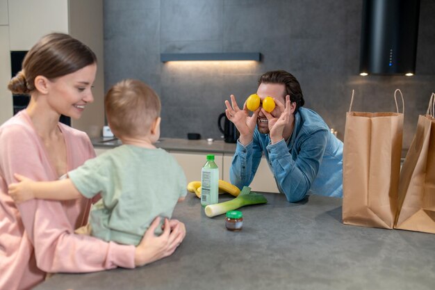 Mamma che tiene in braccio un bambino e papà che lo fanno ridere