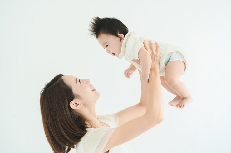 Photo 밝은 방에서 아기를 높이 안고 있는 엄마
