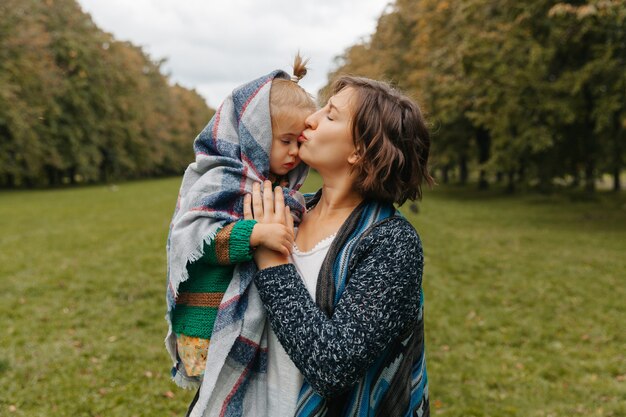 Mom holds daughter in her arms in the park. woman with a small child are walking in the autumn park. autumn.