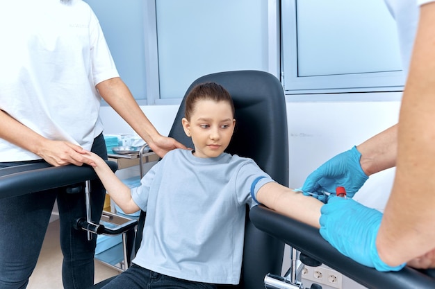 Photo mom holds girl's hand during blood sampling