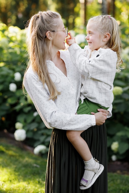 Mom holds her daughter in her arms and communicates with her in the summer in the park