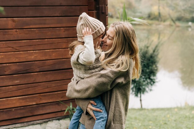 Mom holds her little daughter in her arms outside