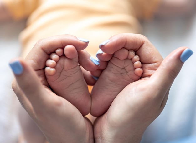 Photo mom holds the legs of a newborn baby in her hands