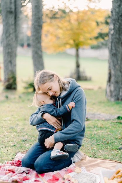 写真 ママは公園の毛布の上に膝に座っている小さな男の子を抱きしめています