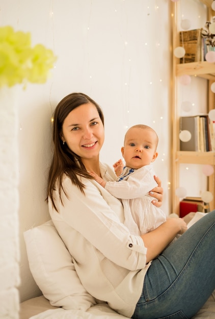 Mom hugs her daughter sitting on the bed